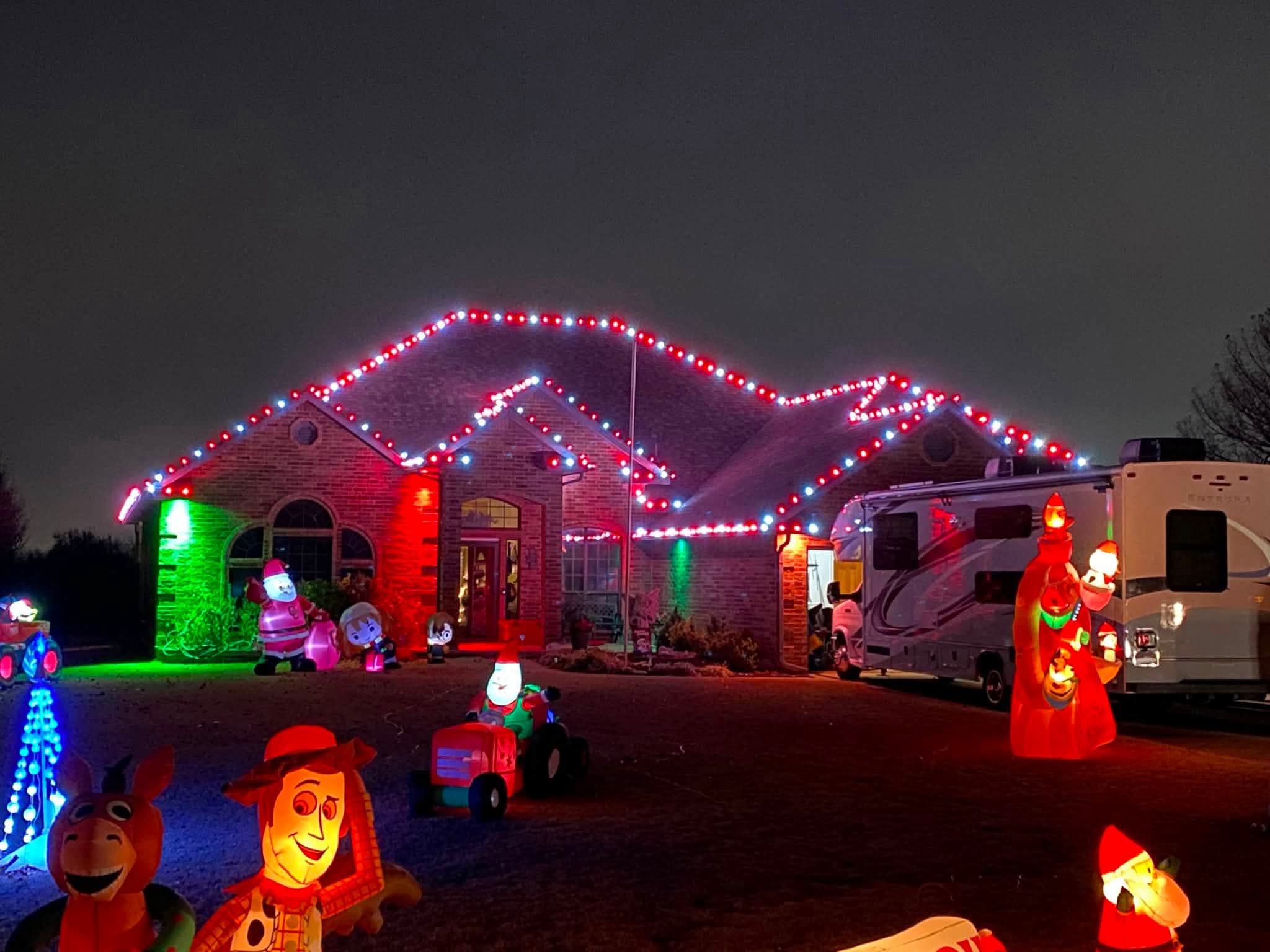 Brick house at night with red and white lights along the roofline